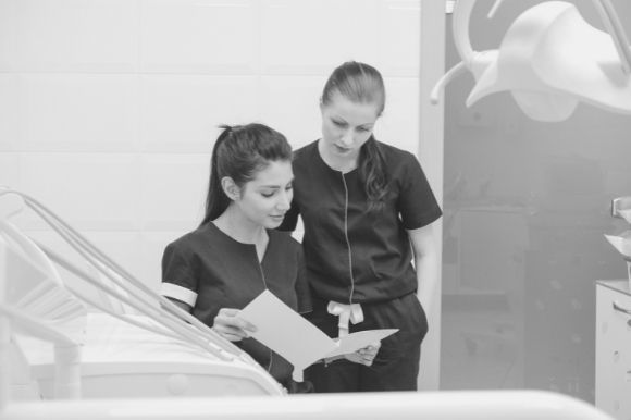Dental assistant reviewing patient records with a colleague.